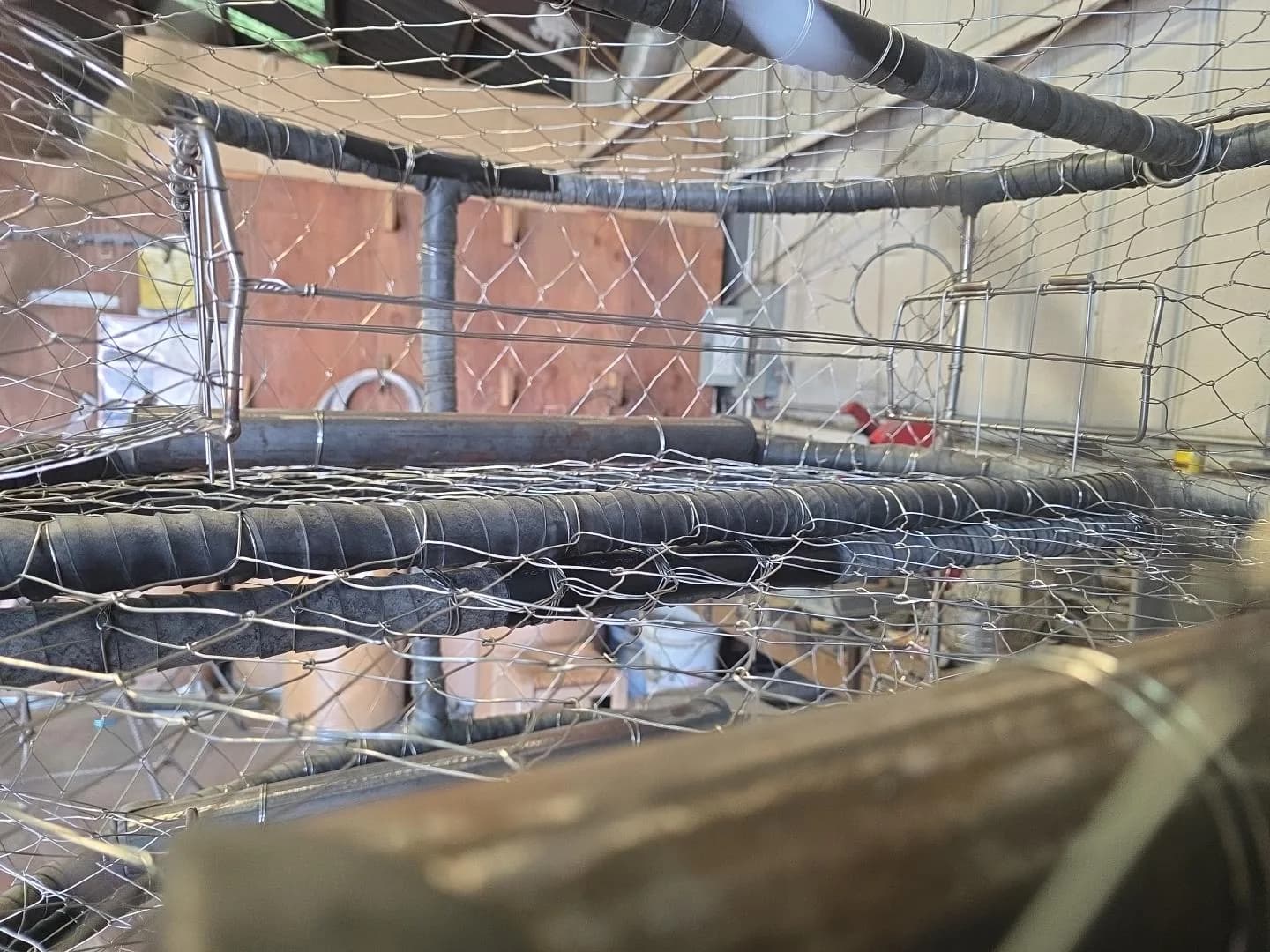 Looking into a wrapped CCP pot showing knitted wire, crossbars and stainless trigger rods at the tunnel opening