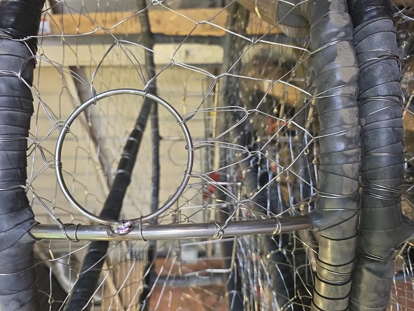 Close view of knitted wire mesh, wrapped frame ring and an escape ring welded to an upright on a CCP pot