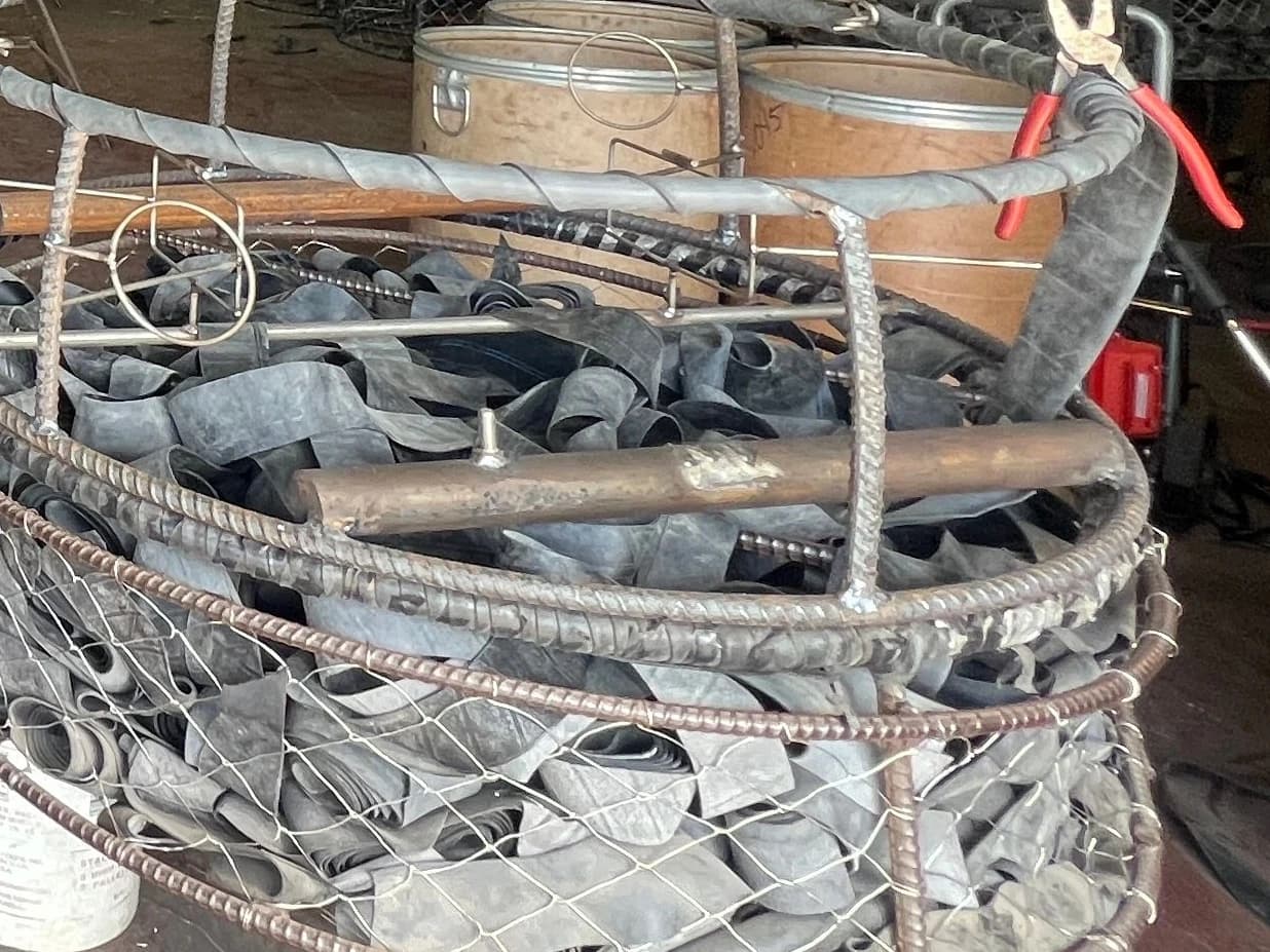 Close view of rebar uprights, welded joints and a round weight bar on frames being assembled