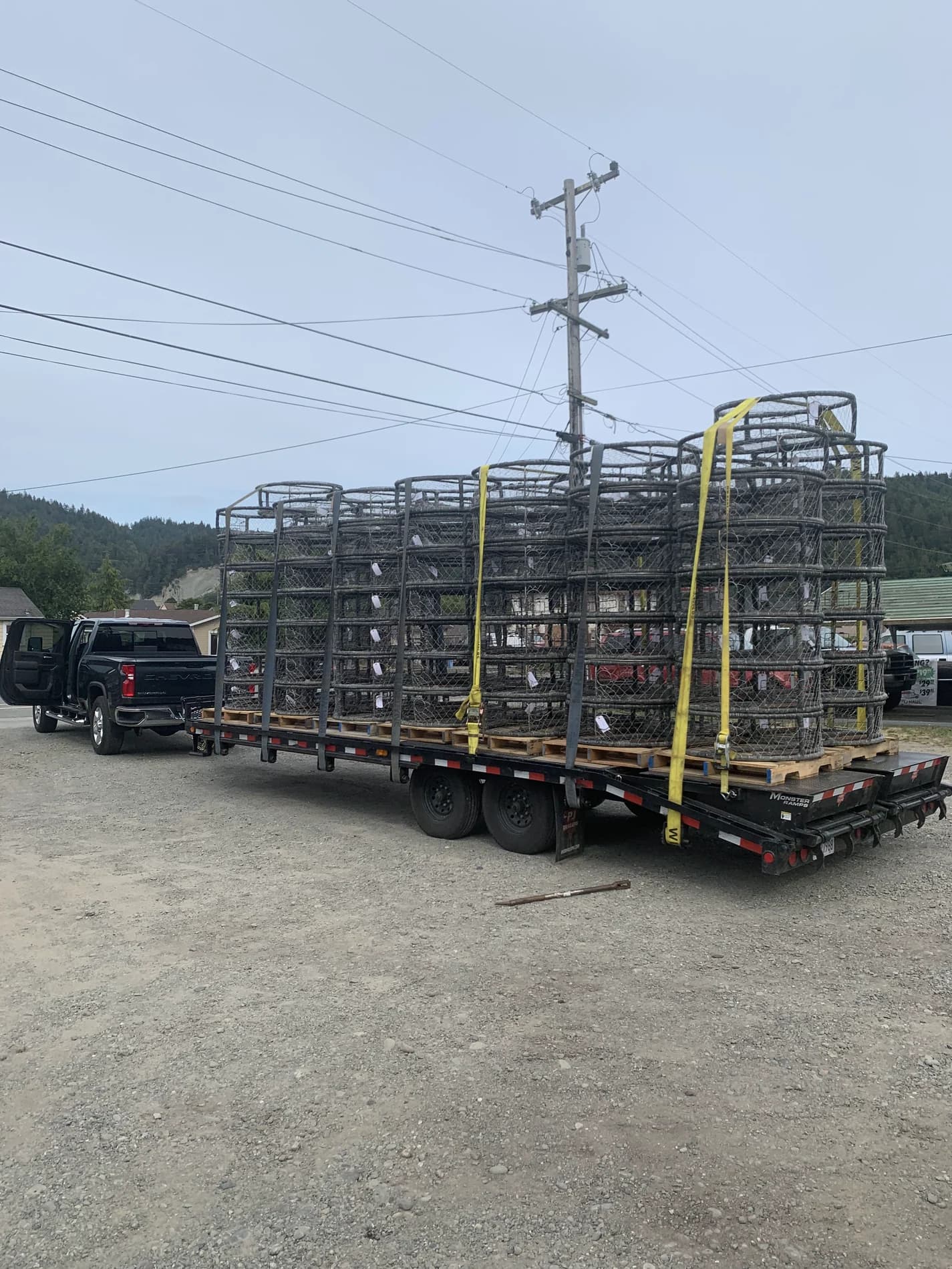 Pickup truck and trailer carrying stacks of CCP crab pots secured with straps