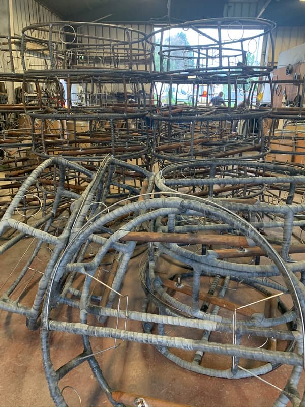 Wrapped crab pot frames on the shop floor with stacks of frames behind them